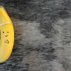 Banan w prezerwatywie, z namalowaną buźką i kciukiem w górę. To zabawne przypomnienie, co to kondomy i jak ważne są w ochronie.
