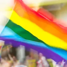 Tęczowa flaga powiewa na wietrze podczas parady, symbolizując dumę i równość, gdy jest dzień LGBT.