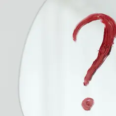 Czerwony znak zapytania namalowany szminką na białym tle.