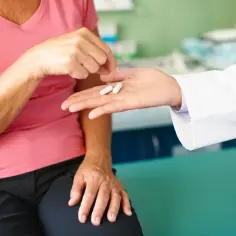 Lekarz podaje pacjentce dwie kapsułki. Może to być związane z nagłym odstawieniem HTZ.
