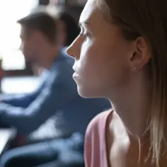 Kobieta z zamyśloną miną, być może zmagająca się z myślami typowymi dla osobowości anankastycznej, siedzi przy stole.